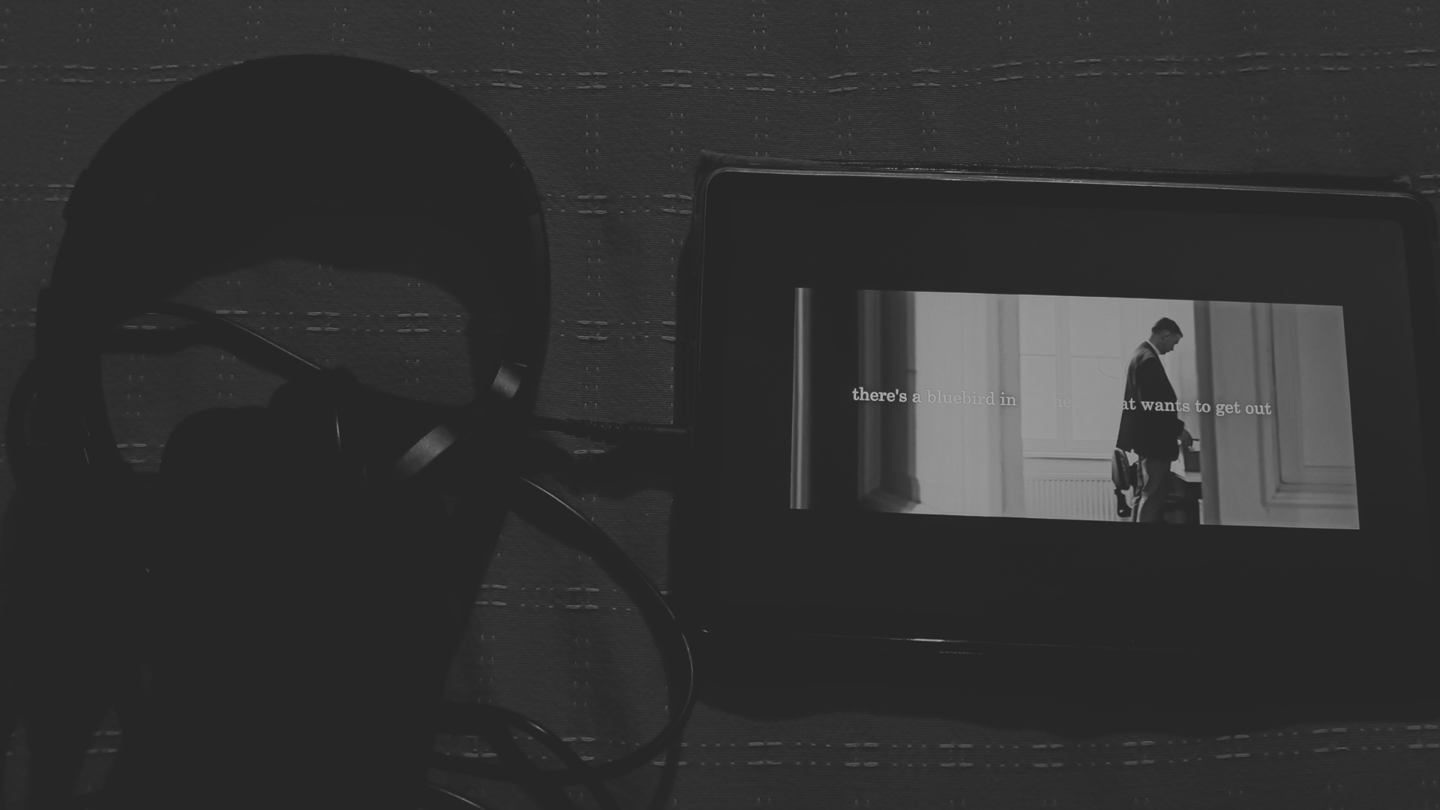 Audífonos y pantalla con cita de Bukowski, atmósfera **oscura** en B&N.