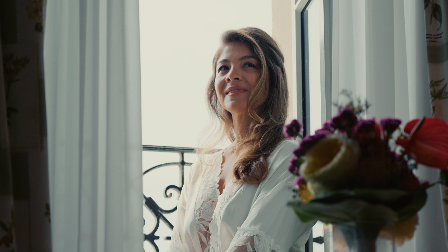 Mariée en robe de chambre en dentelle regardant par la fenêtre le jour de son mariage