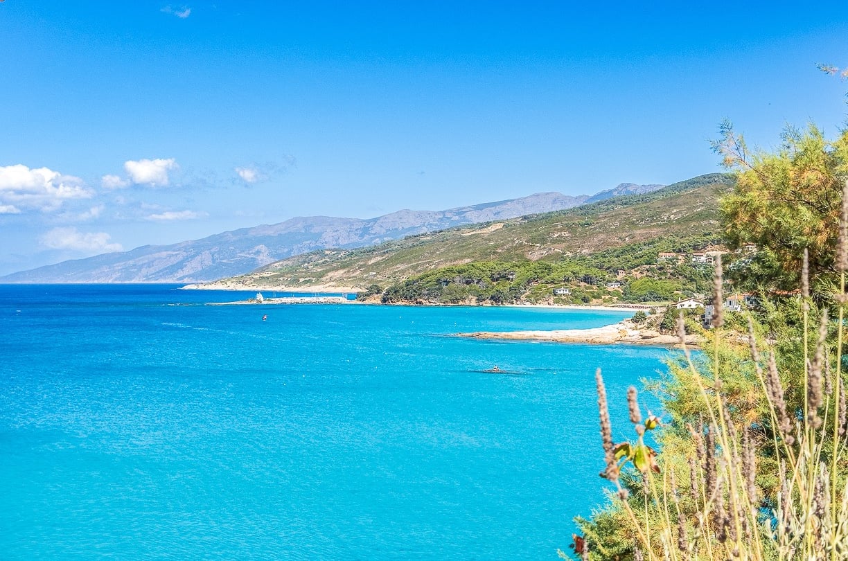 a view of a beach of Ikaria with a blue sky and a few clouds