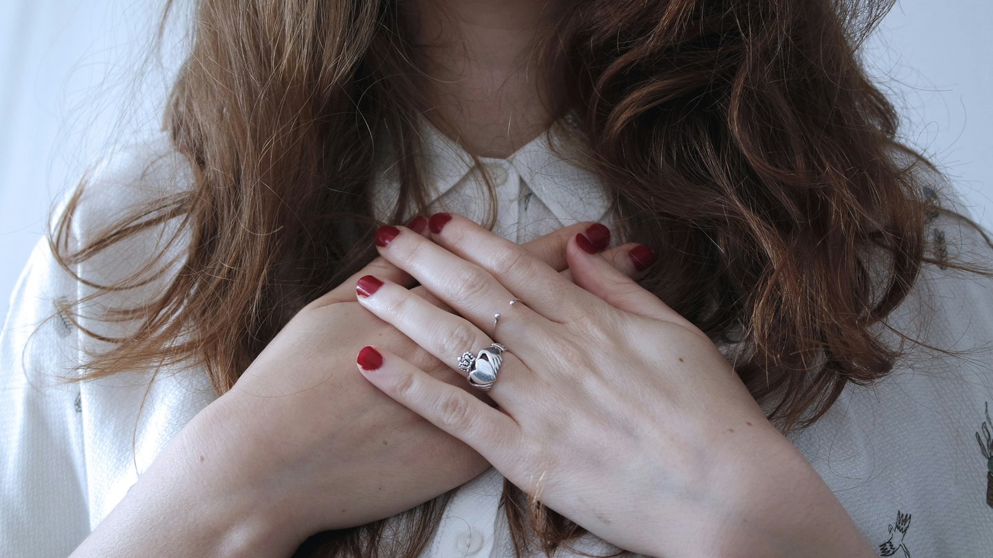 a woman with red nails with her hands on heart