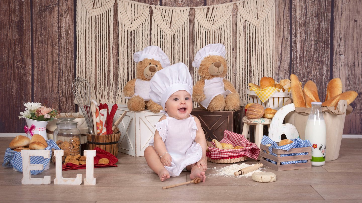 a baby in a chef hat and a teddy bear