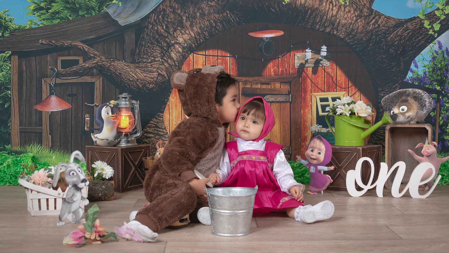 a baby girl in a pink dress sitting on a wooden floor