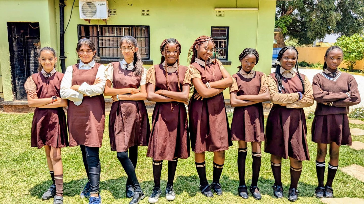 a group of girls in school uniforms standing in front of a building