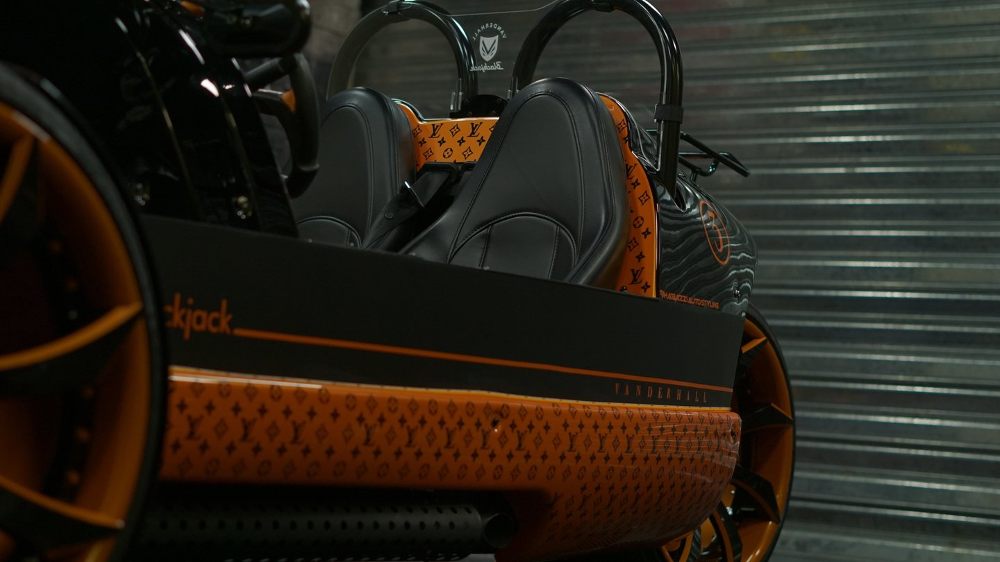 Custom Vanderhall Blackjack three-wheel autocycle with luxury leather seats and orange monogram wrap.