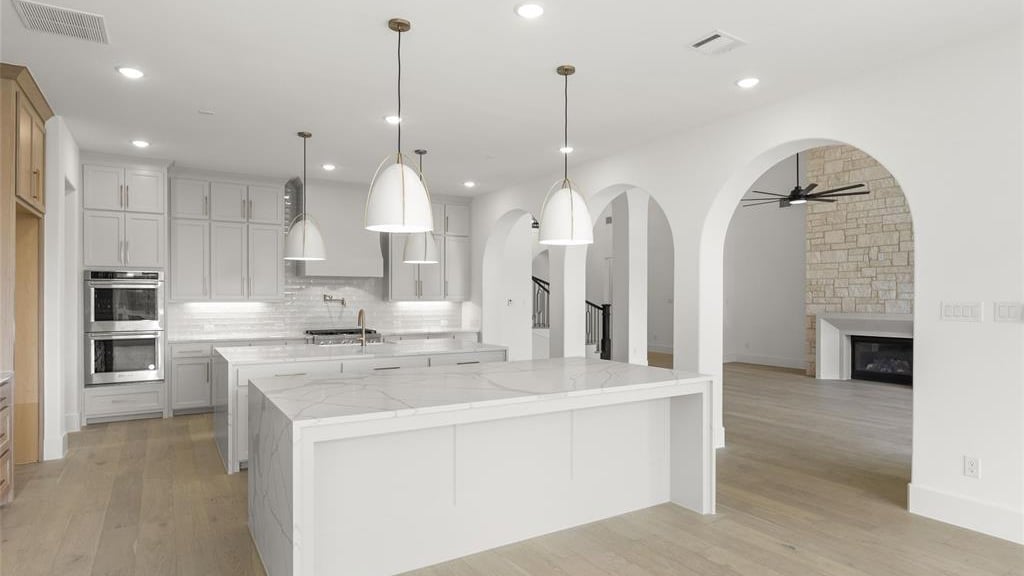 a kitchen with a marble counter top and a large island showing the ac grilles in the ceiling