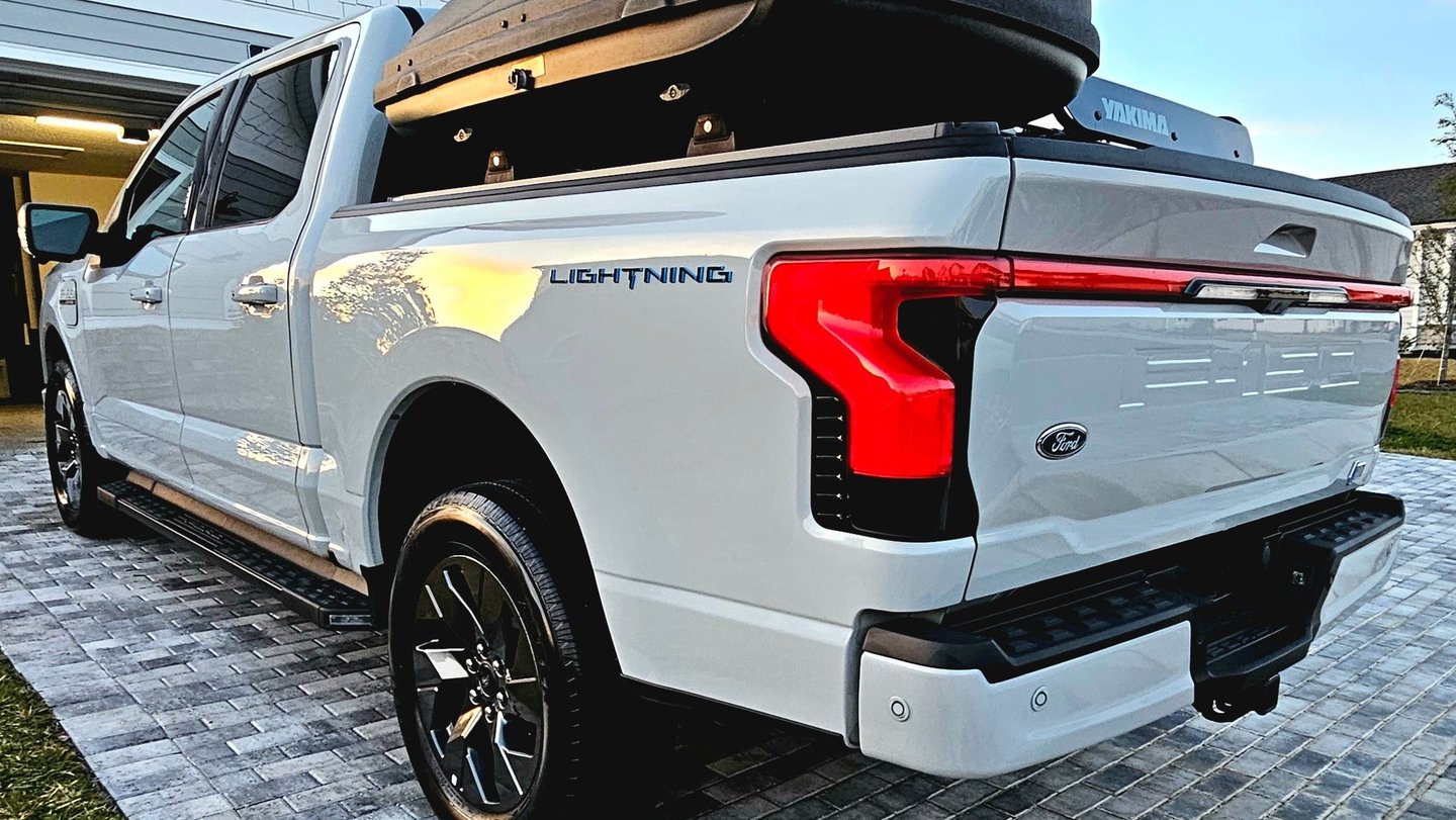 a white truck with a black roof and a luggage case
