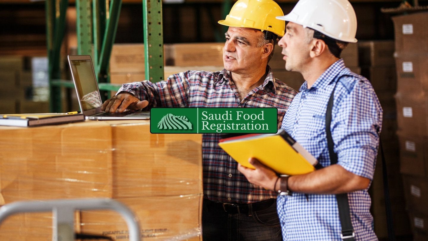 warehouse workers reviewing shipment documents on a laptop, representing customs clearance with Saudi Food Registration.