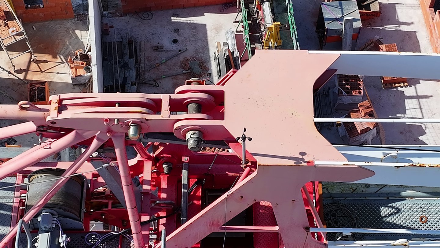 Vue aérienne d'un assemblage de grues à tour industrielle rouge sur un chantier résidentiel.