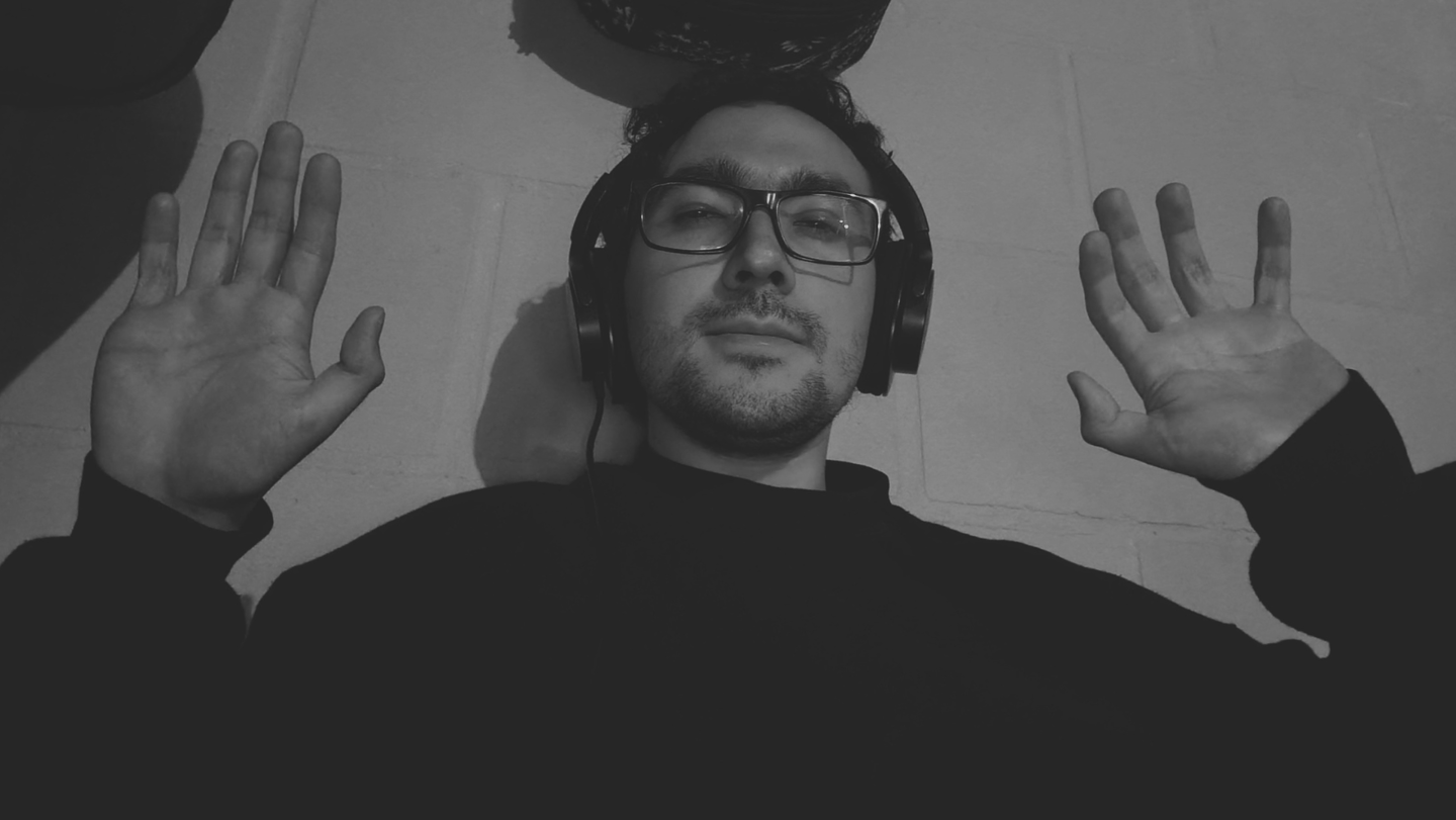 Imagen en blanco y negro de hombre con audífonos y manos levantadas.