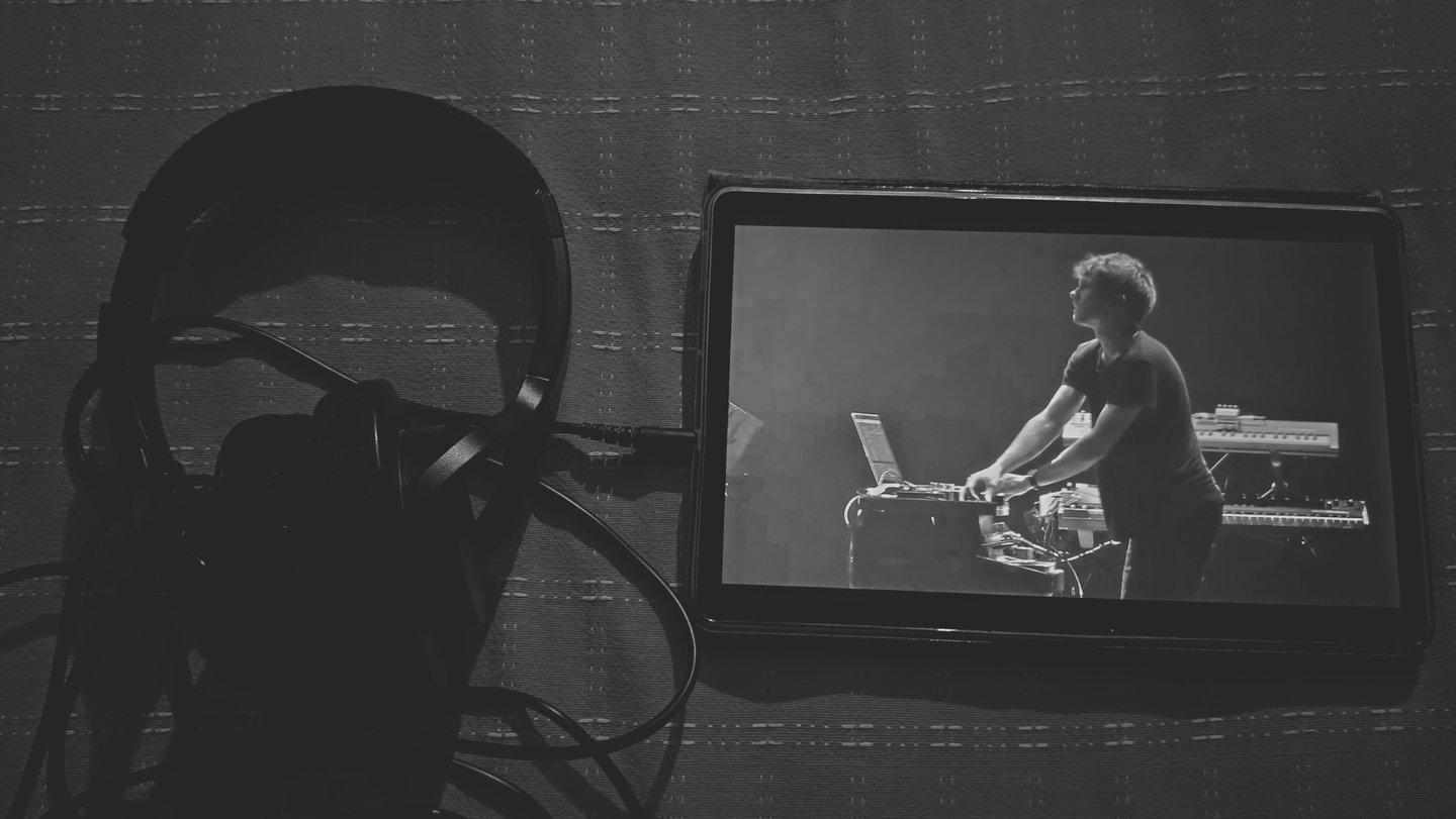 Tablet mostrando video de músico en vivo junto a unos audífonos.