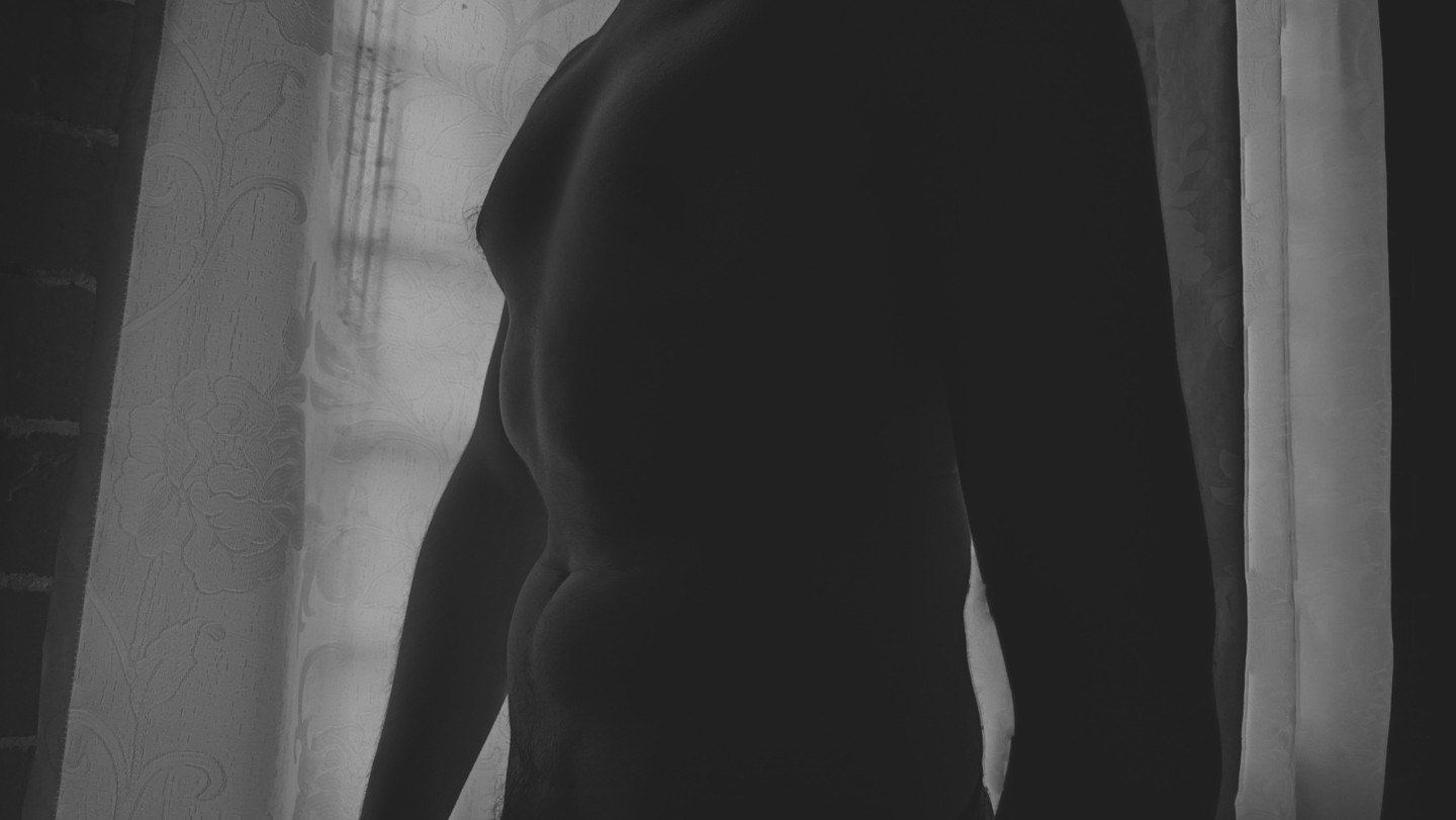 Fotografía desnudo artístico masculino en blanco y negro frente a una ventana.