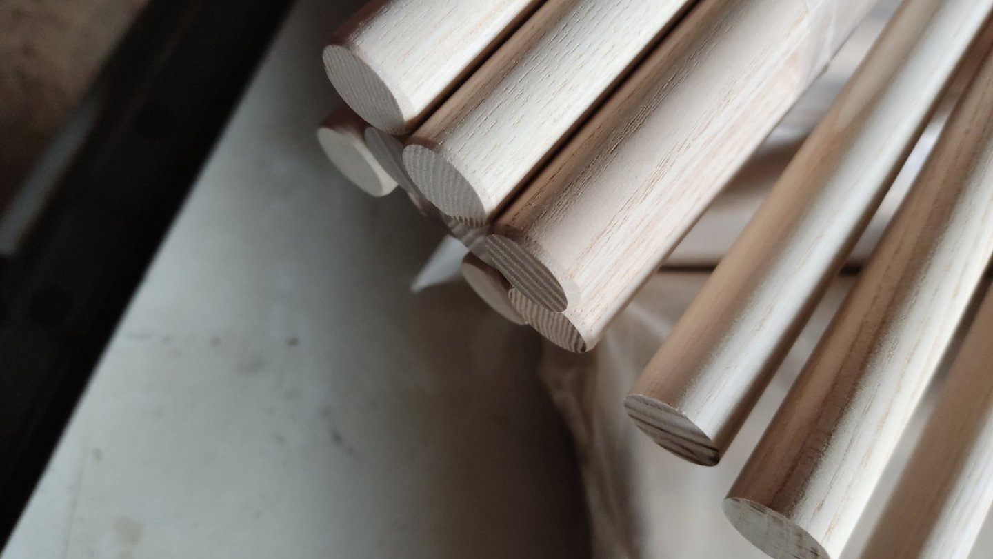 Close-up of smooth unfinished wooden dowel rods stacked for woodworking and DIY craft projects.