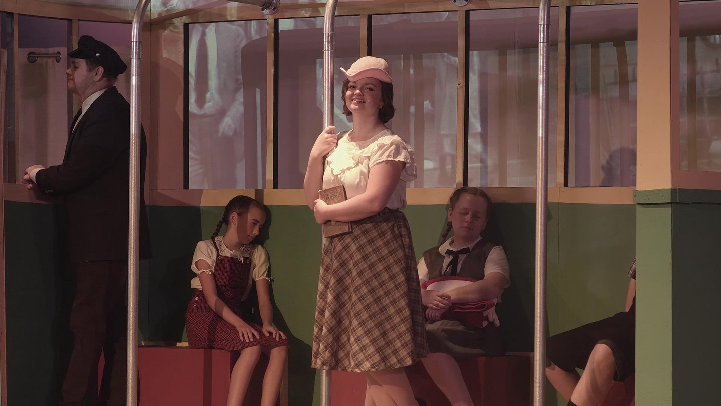 Character Young Catherine on a streetcar accompanied by younger siblings.
