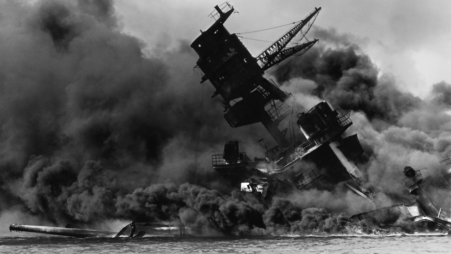 A navy ship up in smoke and sinking after being bombed at Pearl Harbor.