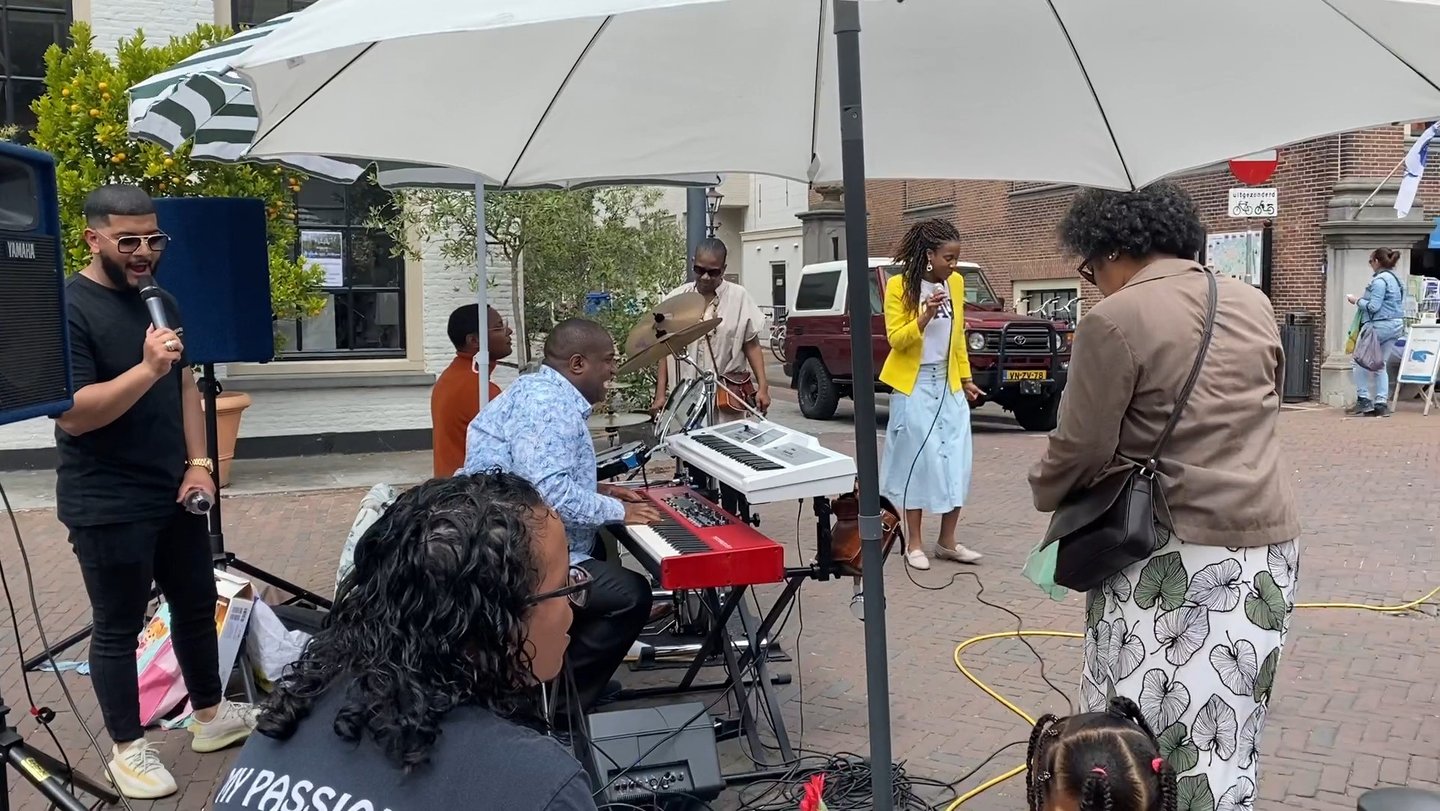 a group of people standing around a piano outside singing
