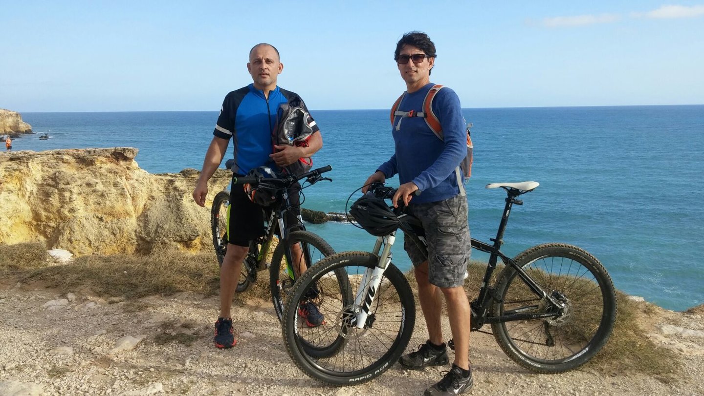 two men standing next to each other on a cliff