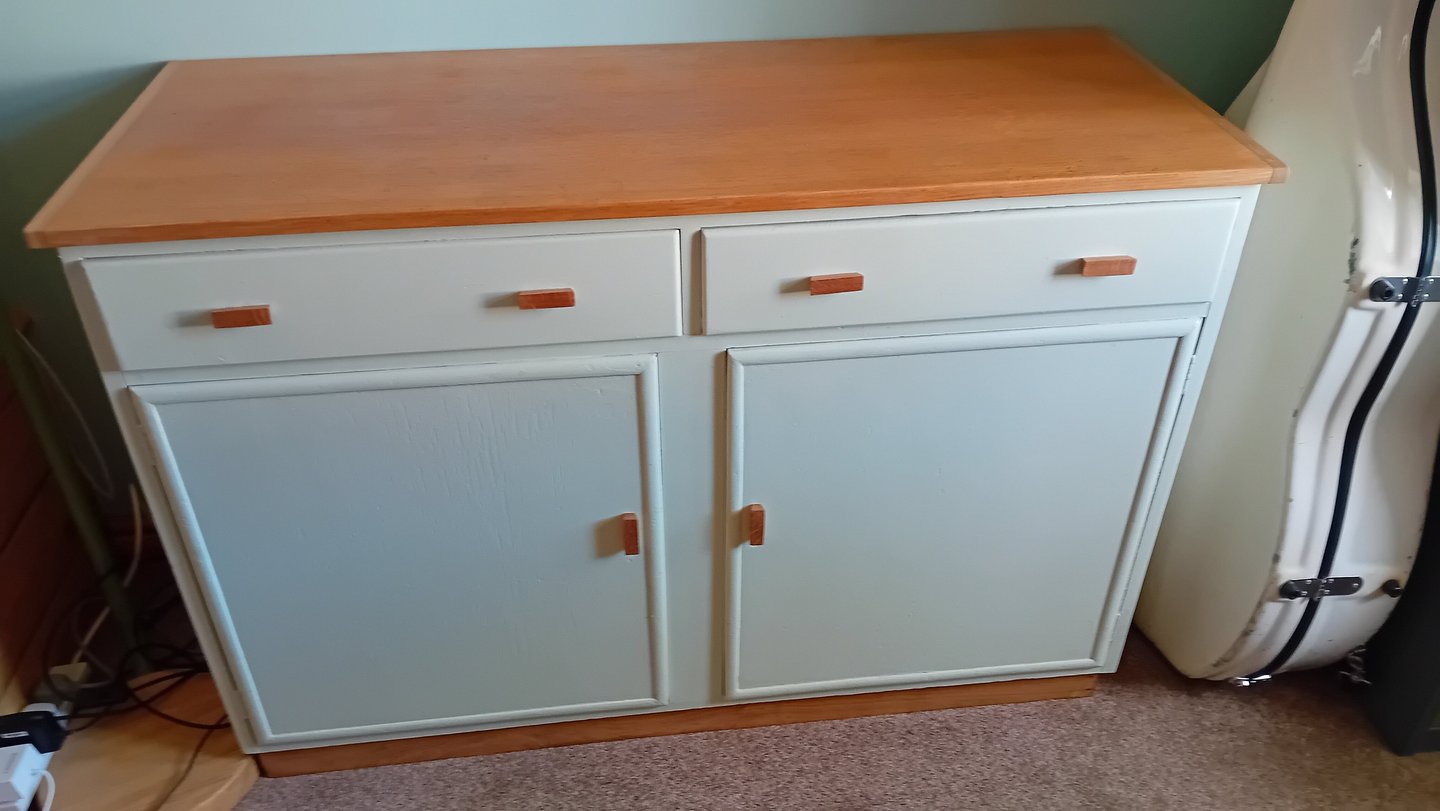 Finished cupboard painted a very light green with natural oak top and handles.