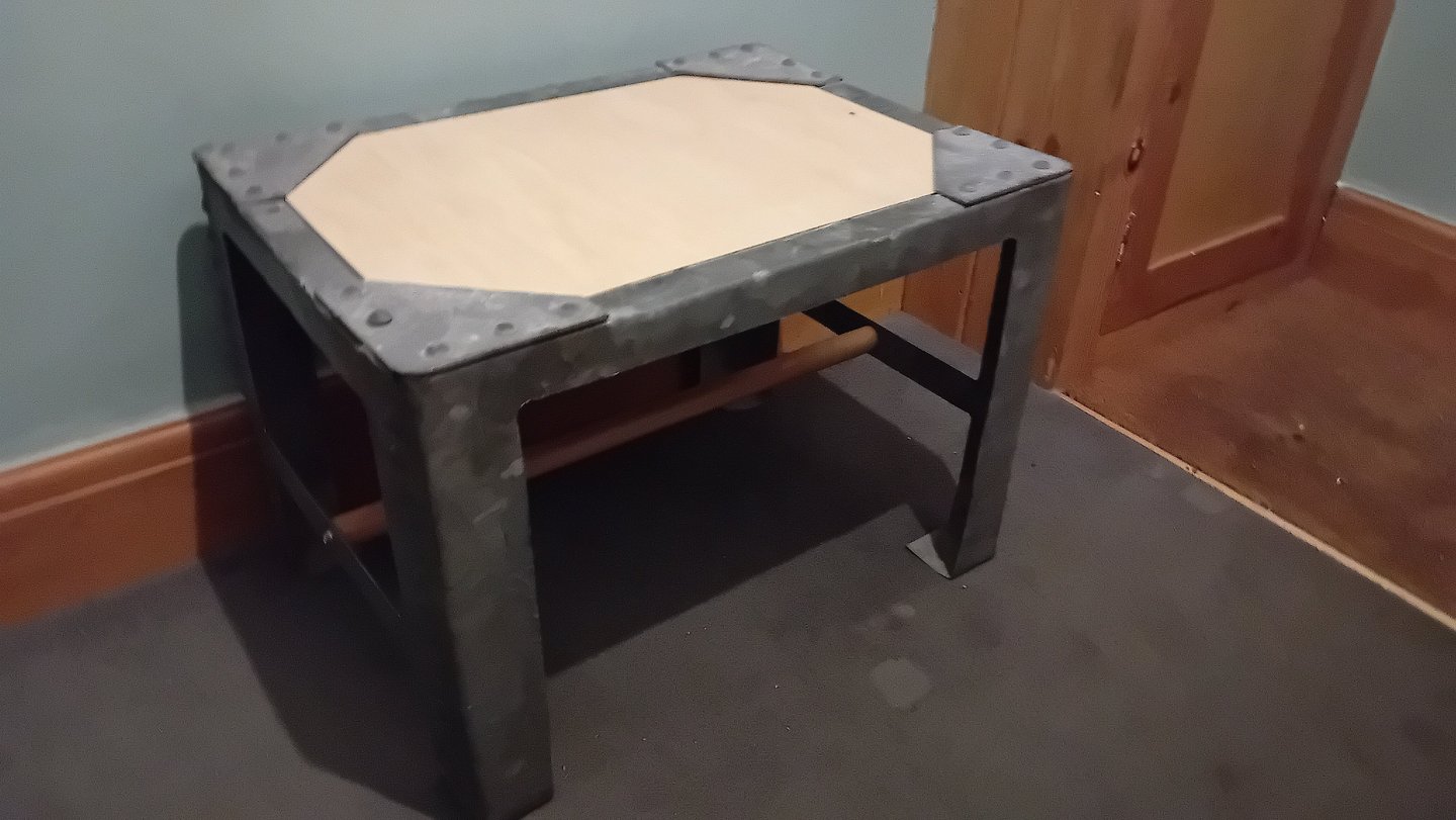 A plywood top has been added under the rivetted corners and wooden bar joining the 2 pairs of legs