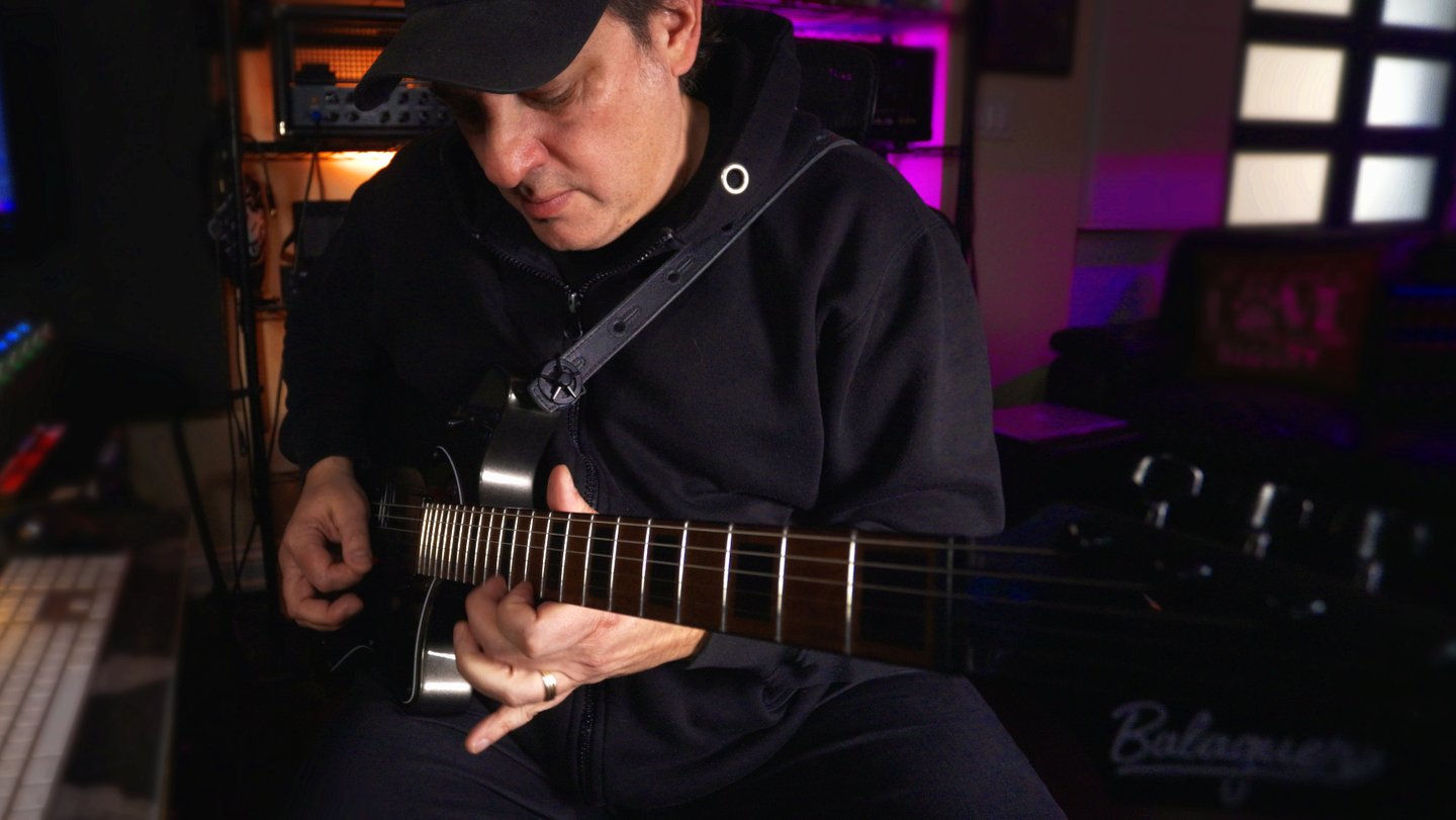 A man in a black hoodie plays an electric guitar in a professional music studio - Lonely Rocker