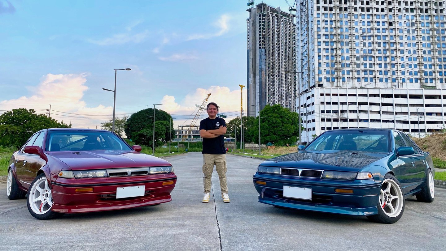 a man standing in the middle of two parked drift cars