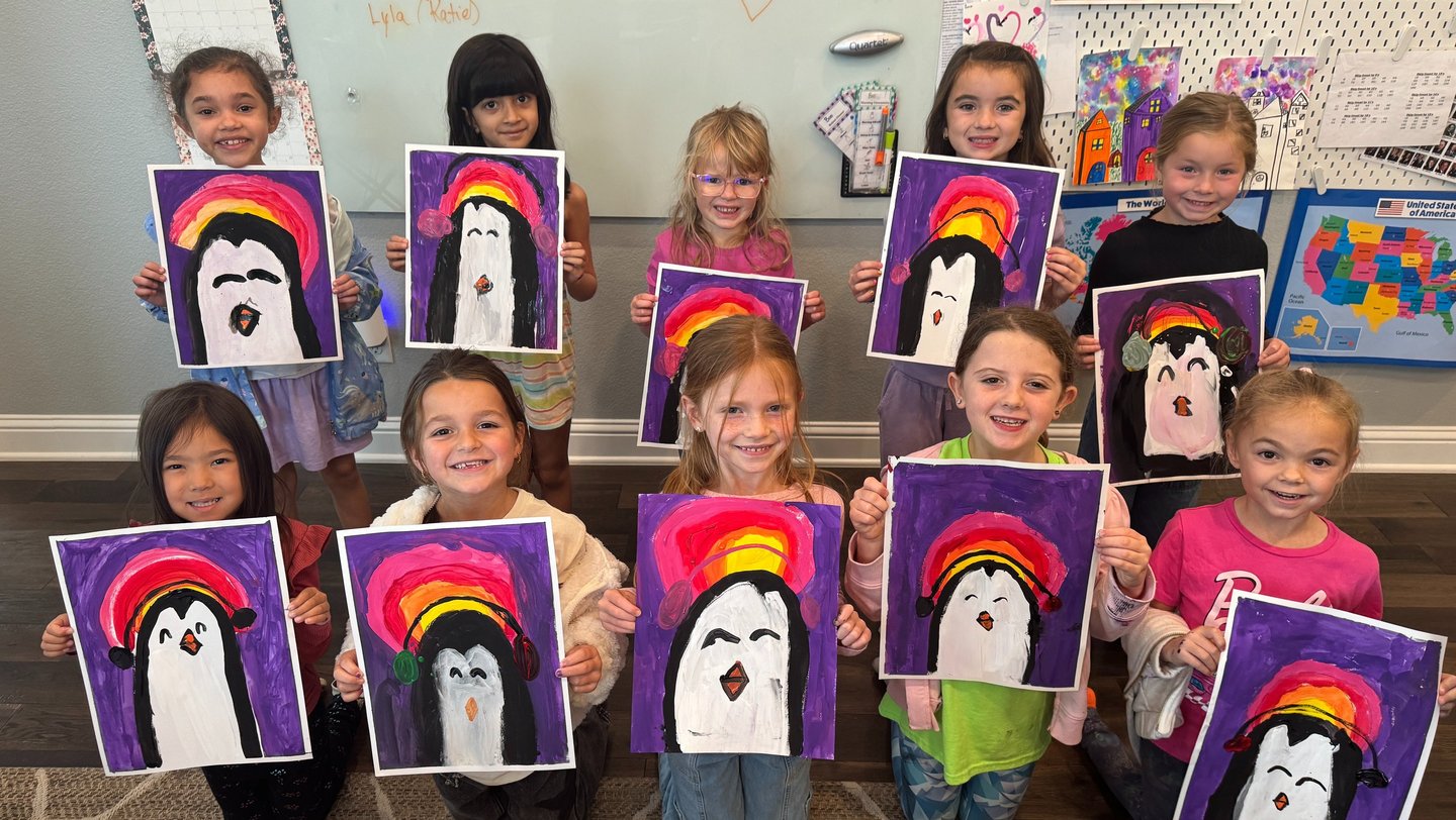 Kids proudly showing their penguin paintings from art classes at Kelley’s Neighborhood Art.