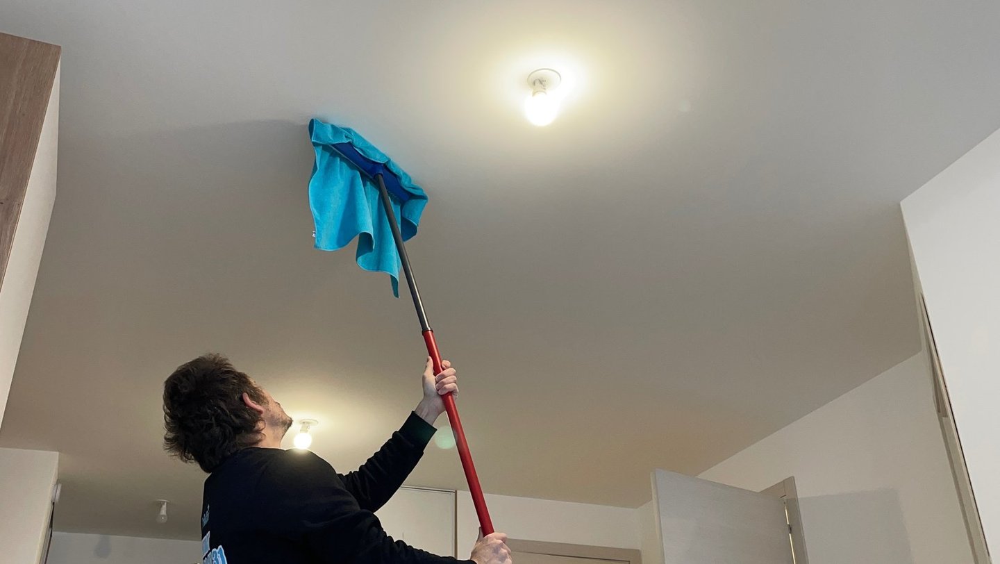 Agent d’entretien, nettoyage plafond avec un balais brosse rouge 