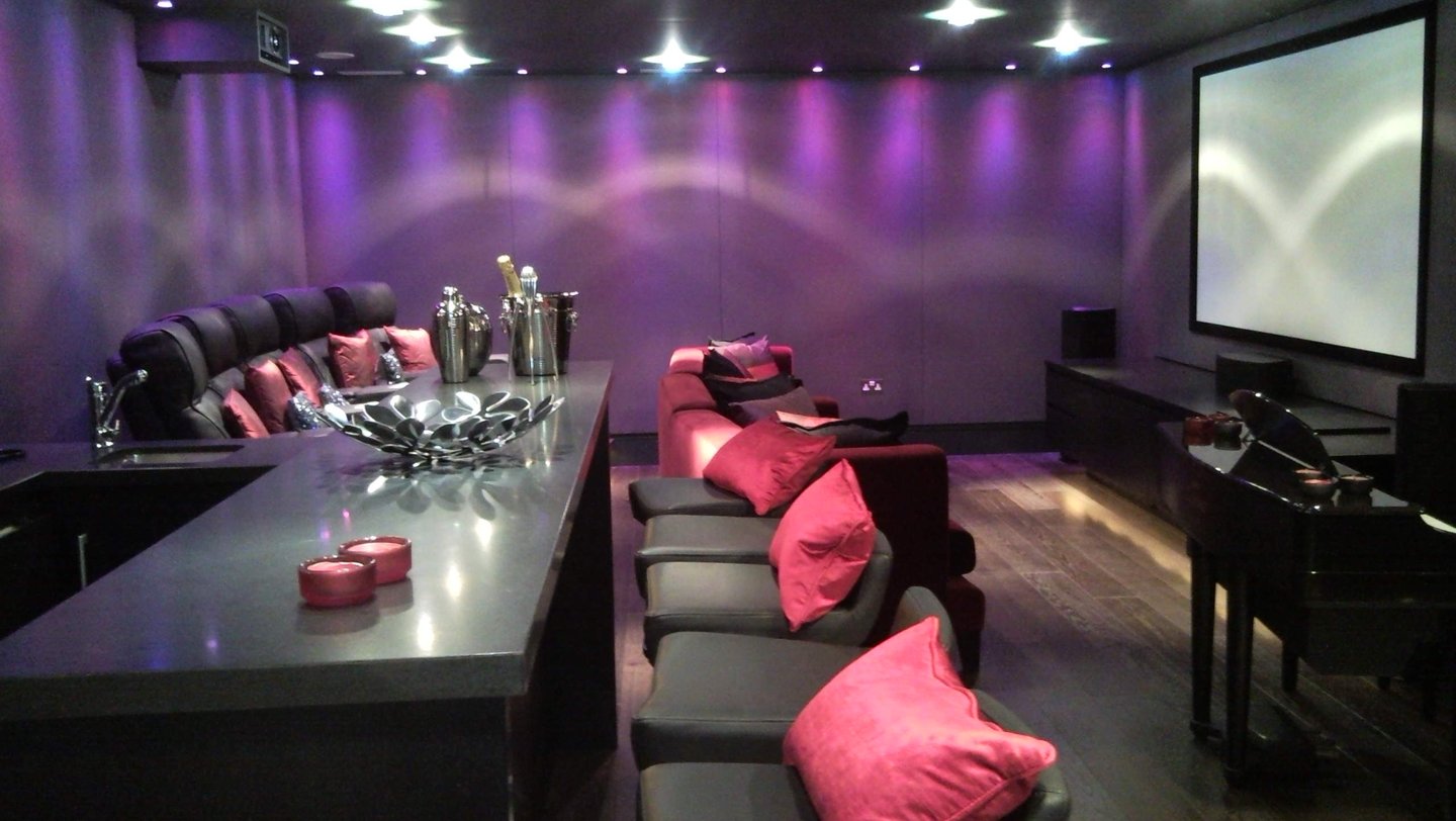 Deep purple stretch-fabric wall finish in a luxury residential home cinema with bar area