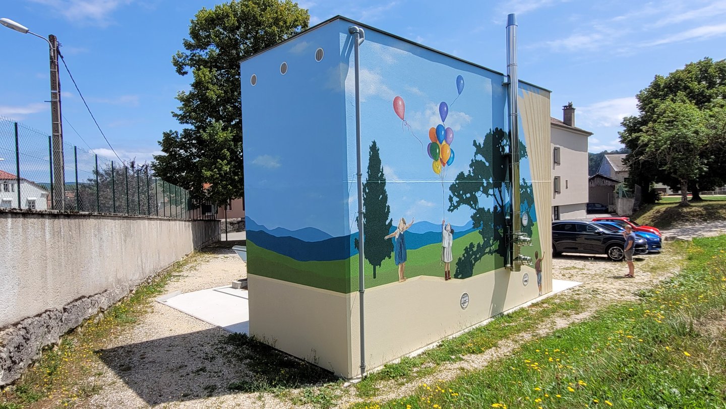 Fresque peinte sur façades. Un paysage simplifié en arrière plan, un muret en trompe-l'oeil.