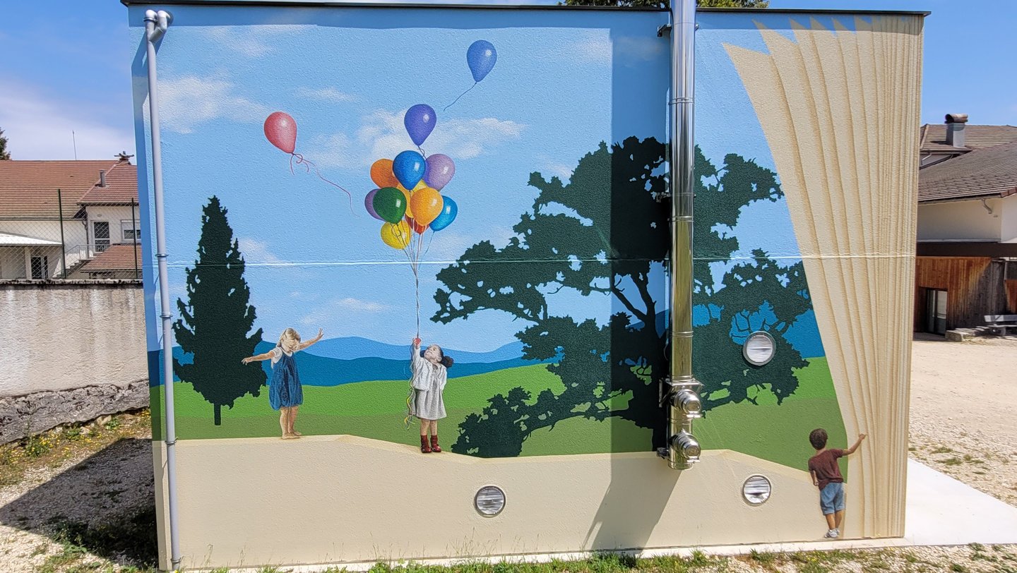 Fresque peinte sur façade. Des enfants jouent sur un muret, un paysage simplifié en arrière plan.