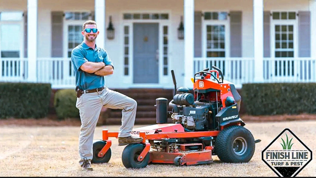 Finish Line Turf and Pest Owner Brandon Morris Standing In Front of house and eqiment. 