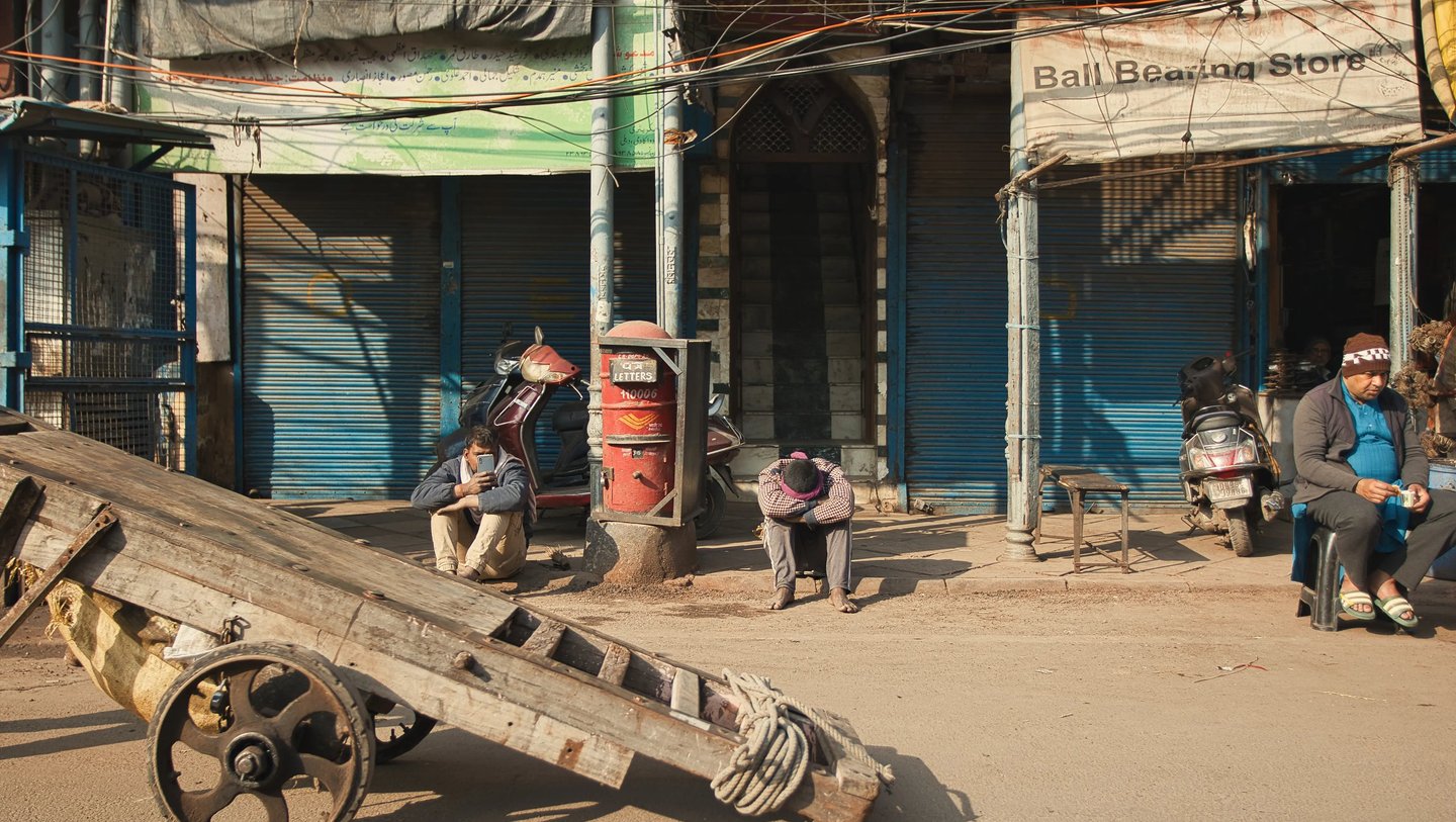 Morning calm on an Old Delhi street with closed shops and resting workers.