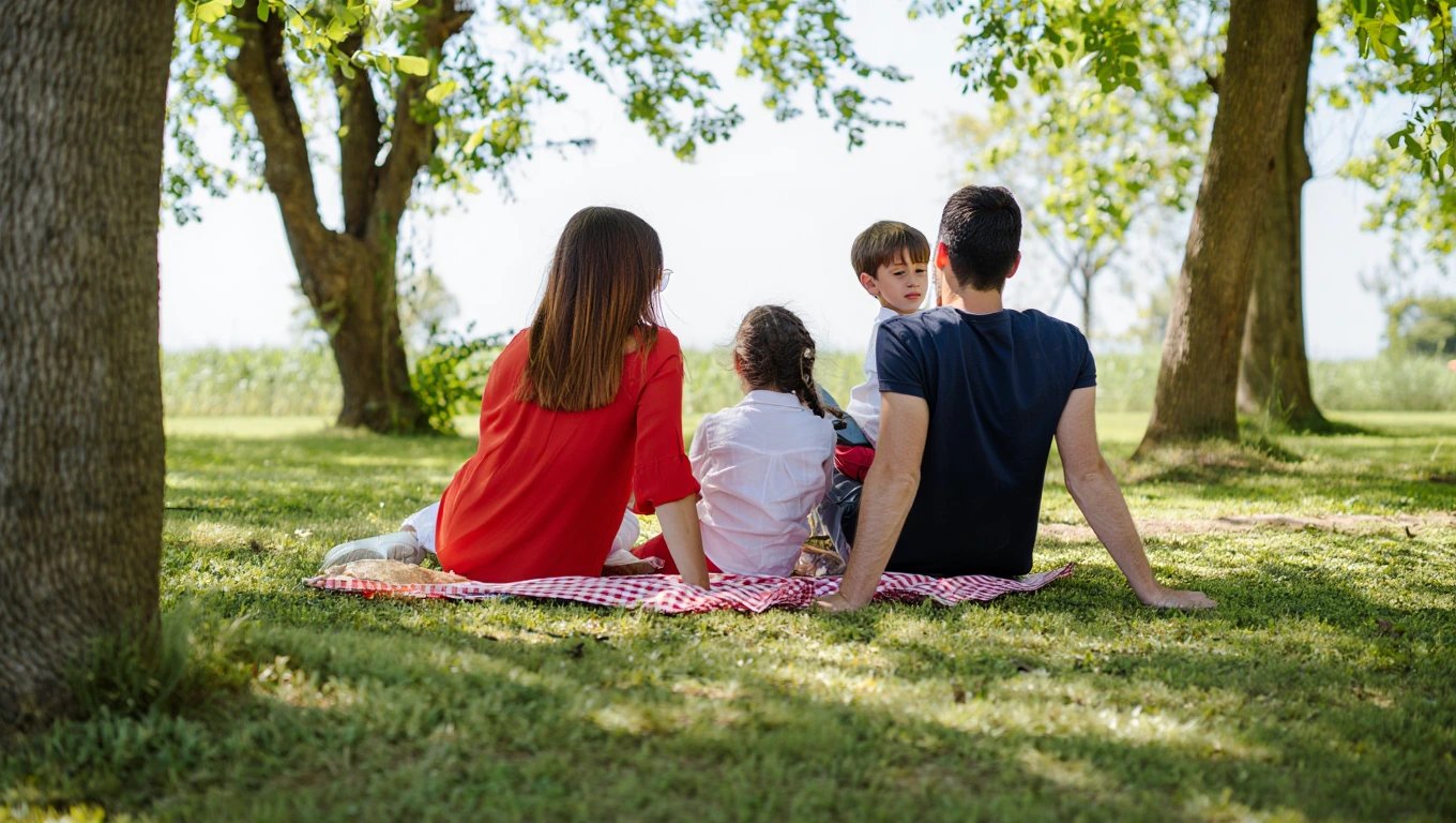 Eine Familie mit zwei Kindern sitzt beim Picknick.