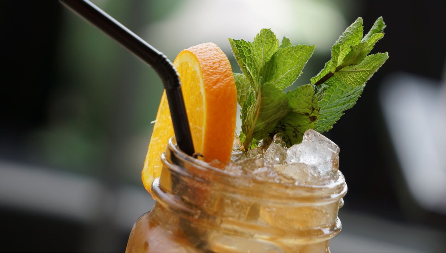 a drink in a mason jar with a strawberries and oranges