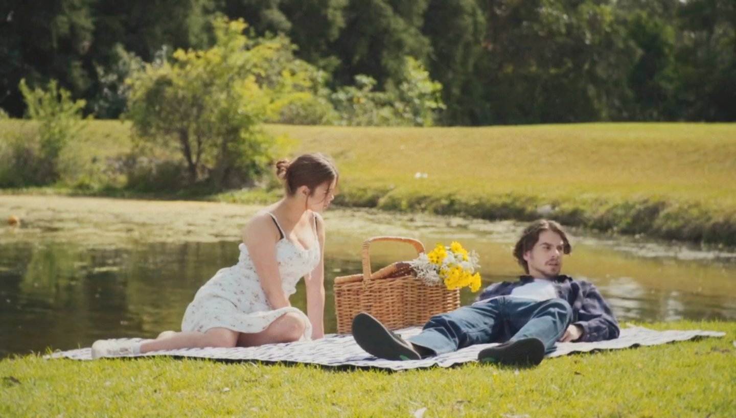 a man and woman sitting on a blanket in the grass