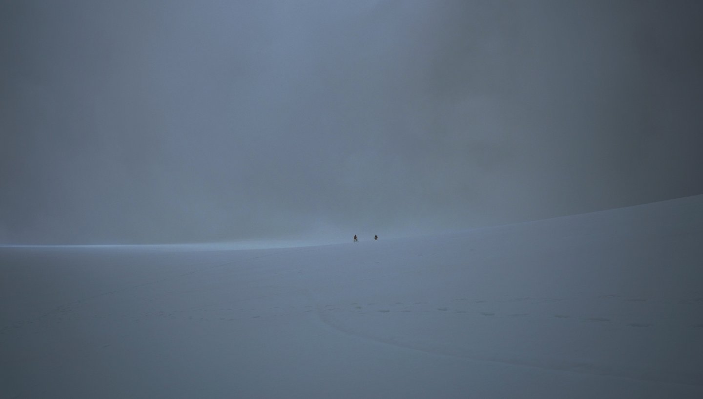 Deux randonneurs dans le brouillard de la Vallée Blanche brièvement éclairés par un rayon de lumière