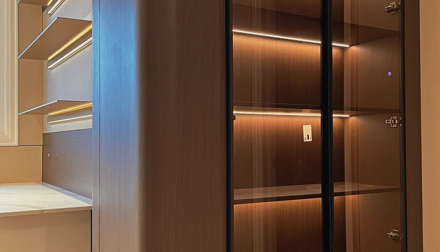 Modern dark wood display cabinet with glass doors and integrated LED shelf lighting.