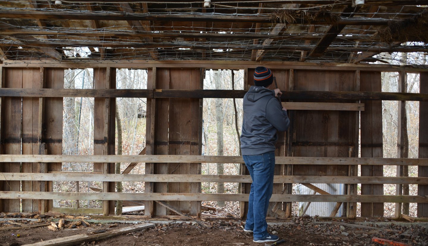 A person prying of wood from a decaying structure