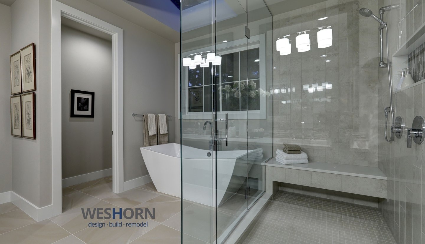 Modern master bathroom featuring a white freestanding soaking tub and glass walk-in shower with bench.