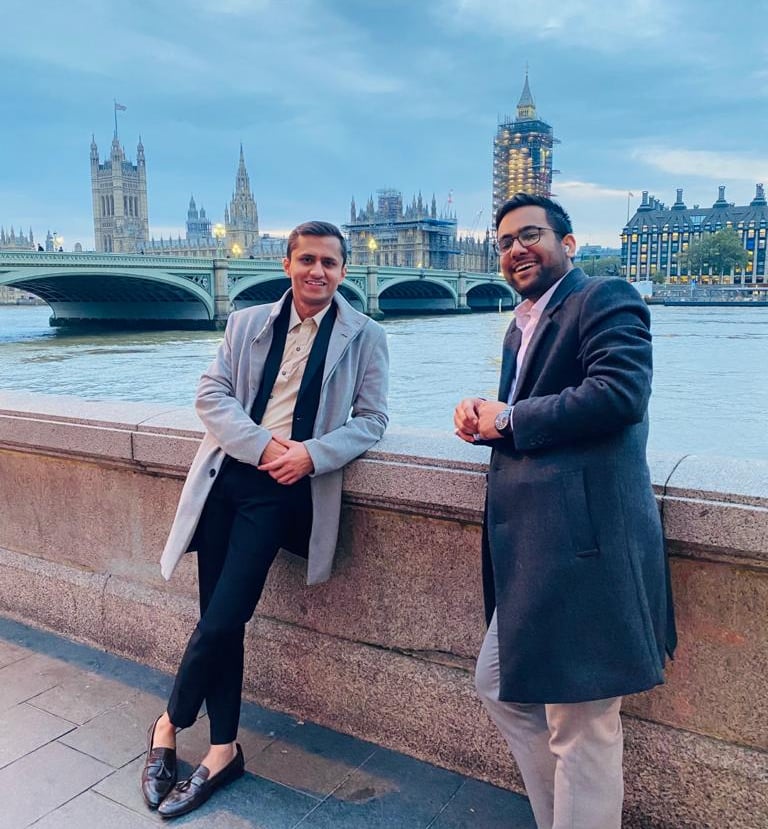two men standing next to each other on a bridge