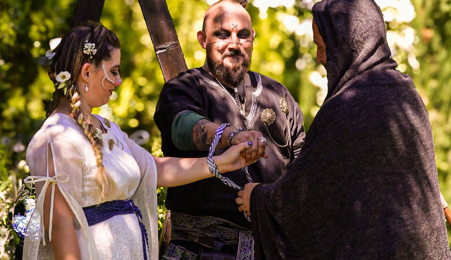 Ceremonia de boda al aire libre con pareja vestida al estilo medieval, atados por una cuerda mientra