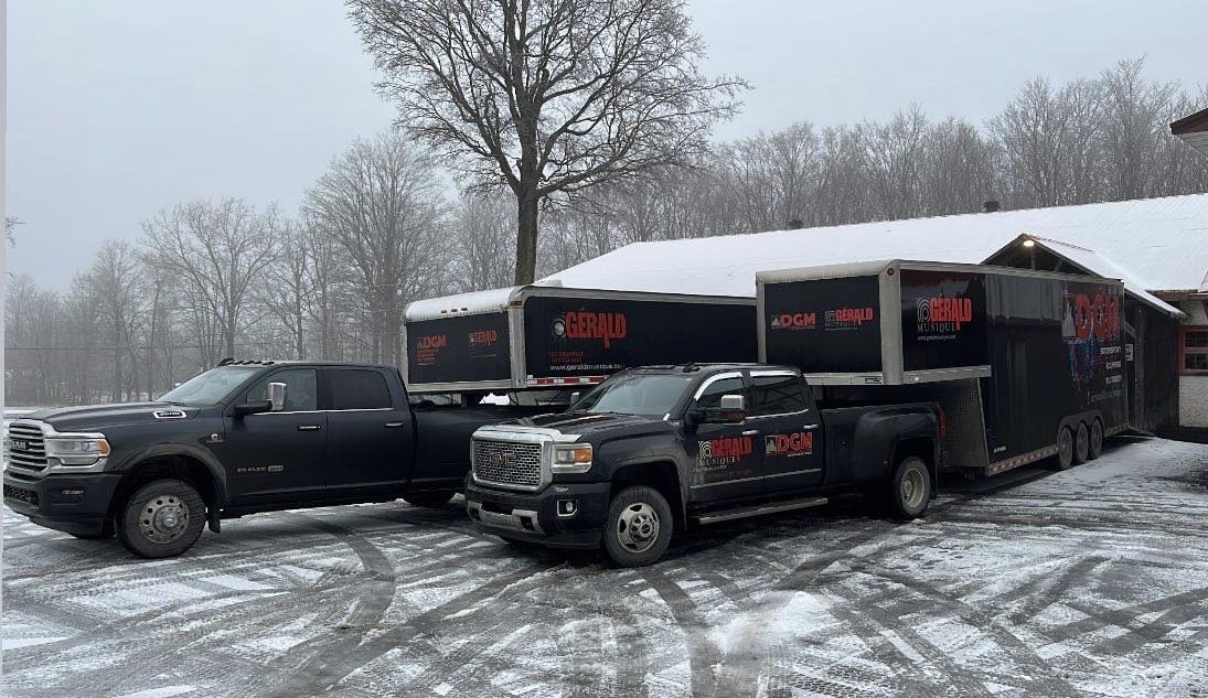Black Ram and GMC dually trucks towing Gerald Musique trailers in a snowy parking lot.