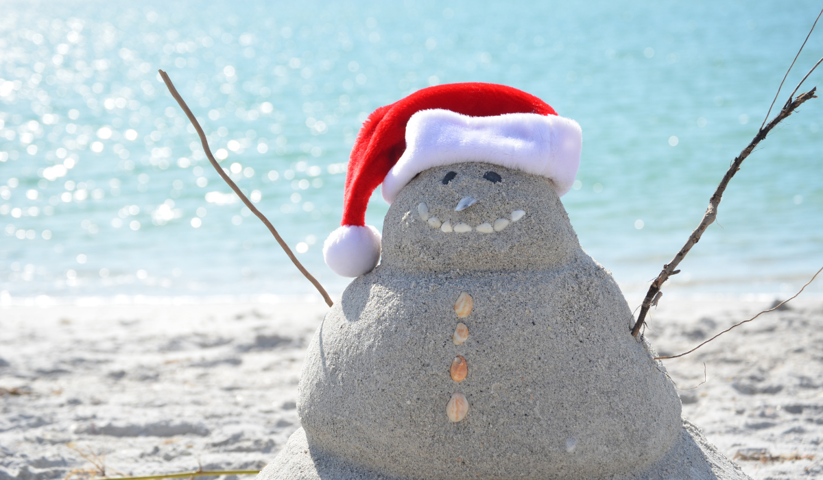 beach snowman made of sand with santa hat