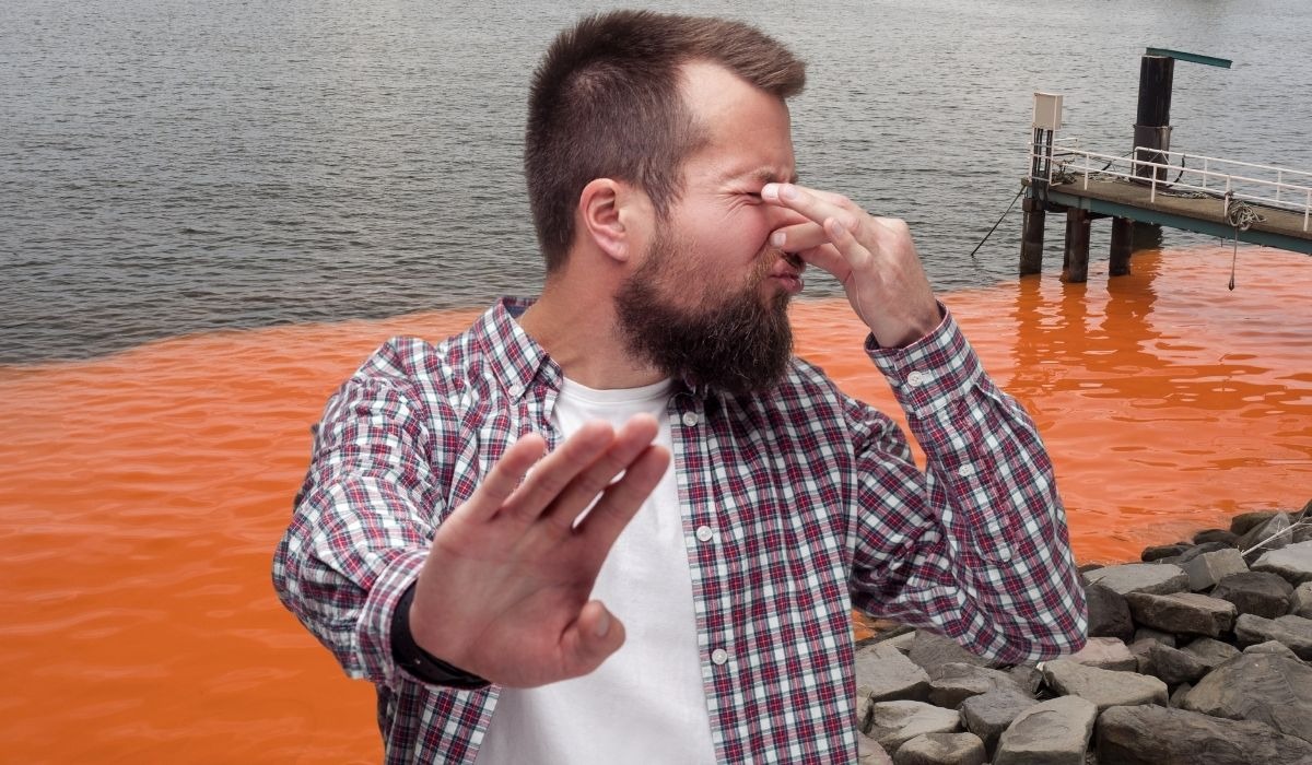 man holding nose from smelly red tide odor