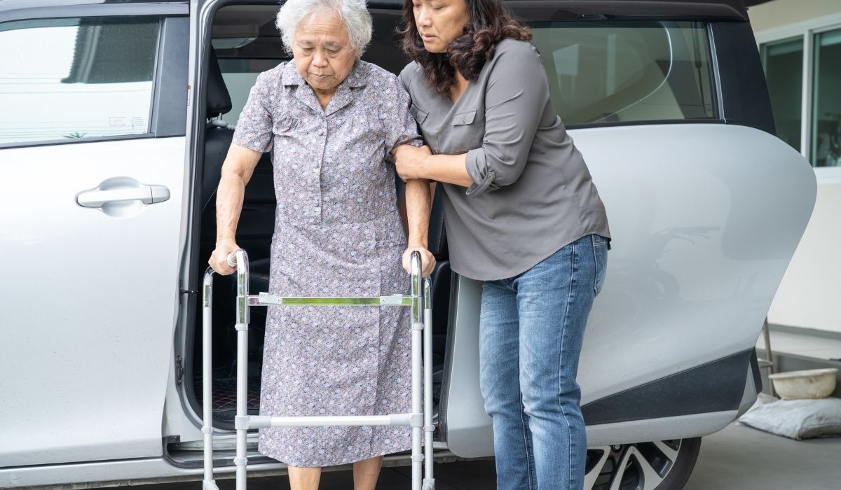 senior asian woman with walker helped by younger woman