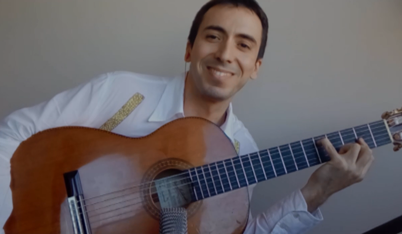 Paco sonríe mientras muestra su guitarra.