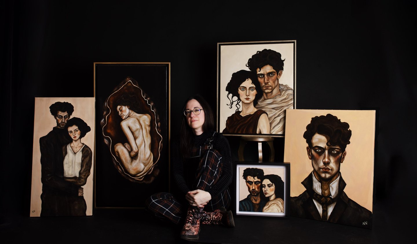 Artist manef photographed with a selection of original portrait paintings