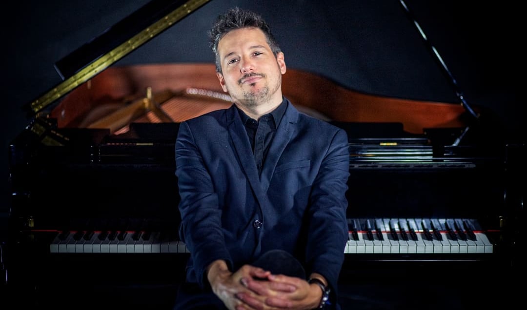 a man in a suit and tie sitting on a piano