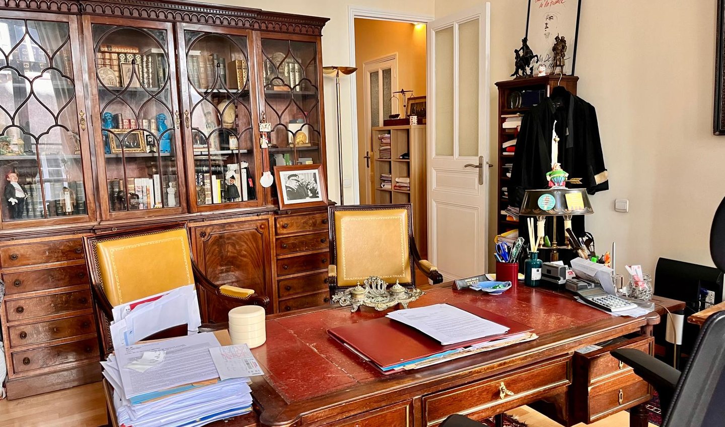 bureau d'avocat avec meubles anciens, bibliothèque, robe d'avocat, dossiers.