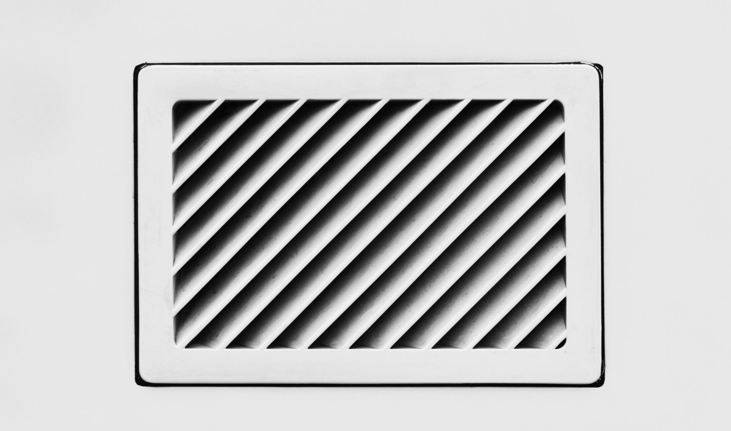 Angled black slats inside a white rectangular vent.
