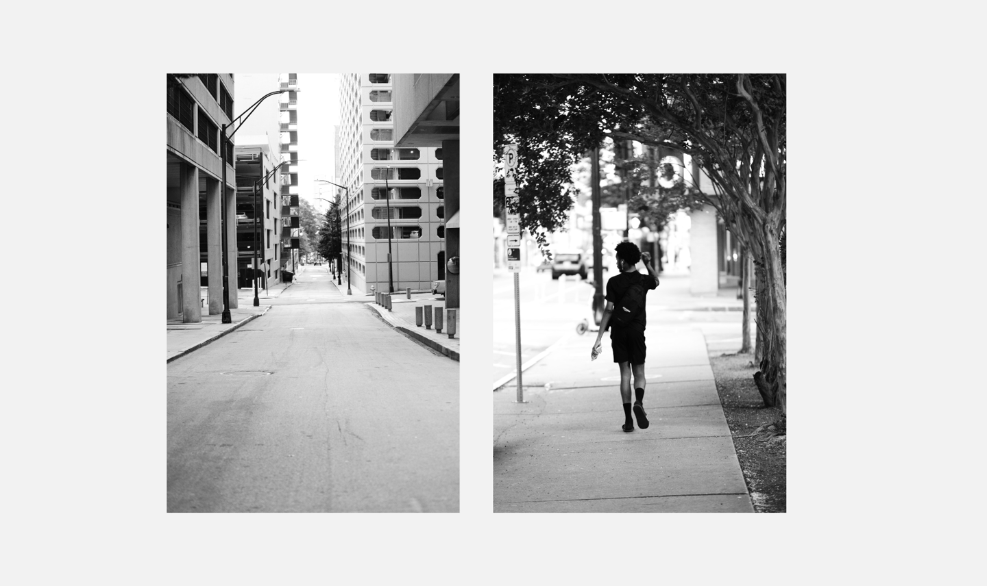Black and white street photography showing an empty city road and a person walking on a sidewalk.